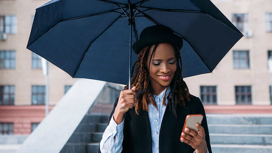 Woman Looking at her Phone and holding an Umbrella