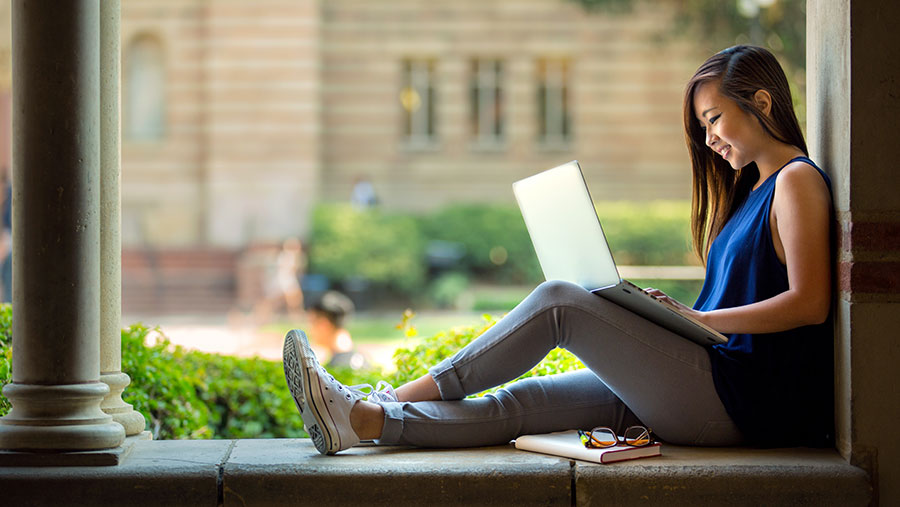 Student writing on laptop computer