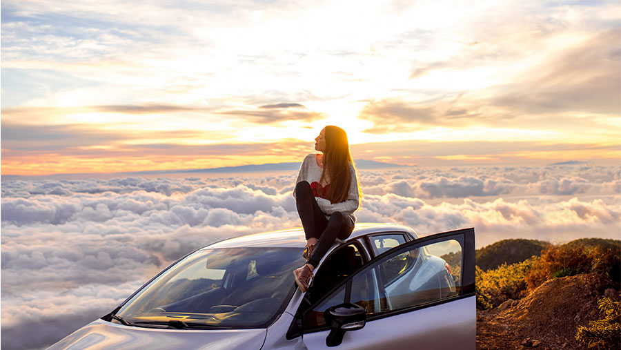 Woman sitting on top of her car