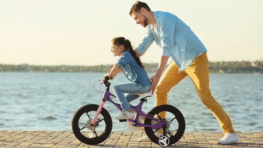 Father teaching his daughter how to ride a bike