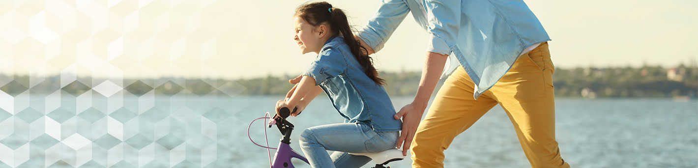 Girl riding bike next to father.