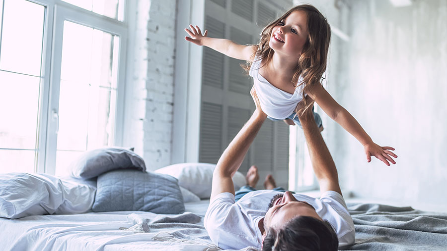 Father and daughter playing on bed