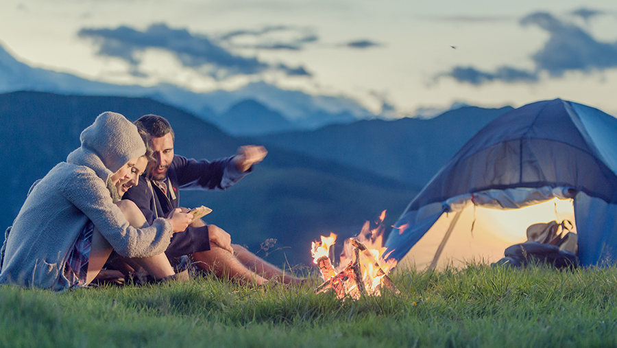 Friends camping by fire and tent